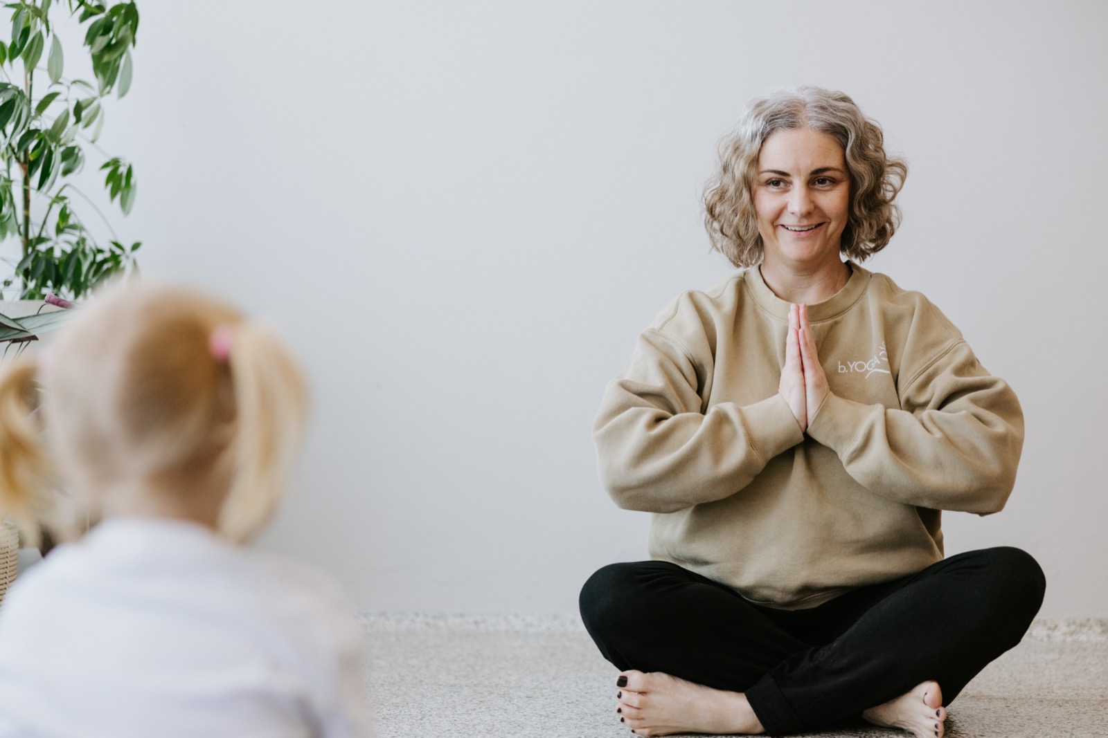 Heidi seated with a child during a kids holiday class at b.YOGA Practice