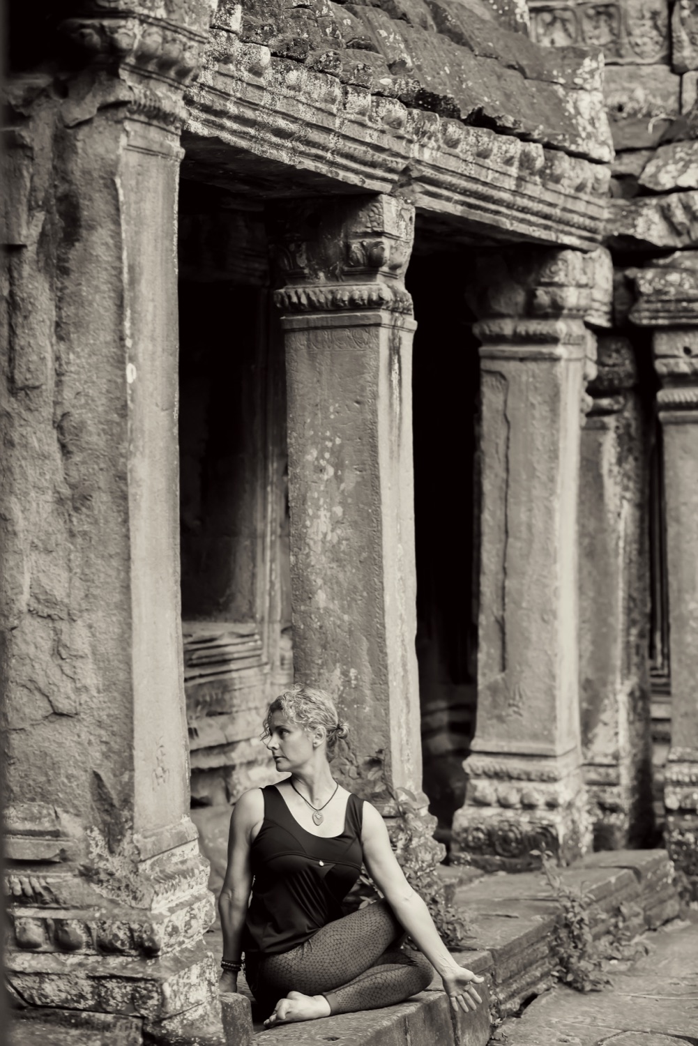 Heidi seated in quiet meditation among the stone columns of Angkor, Cambodia